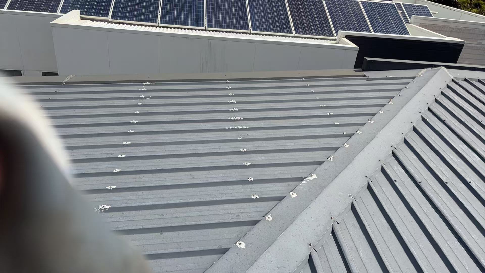 Grey metal roof sheets and ridge detail near solar panels