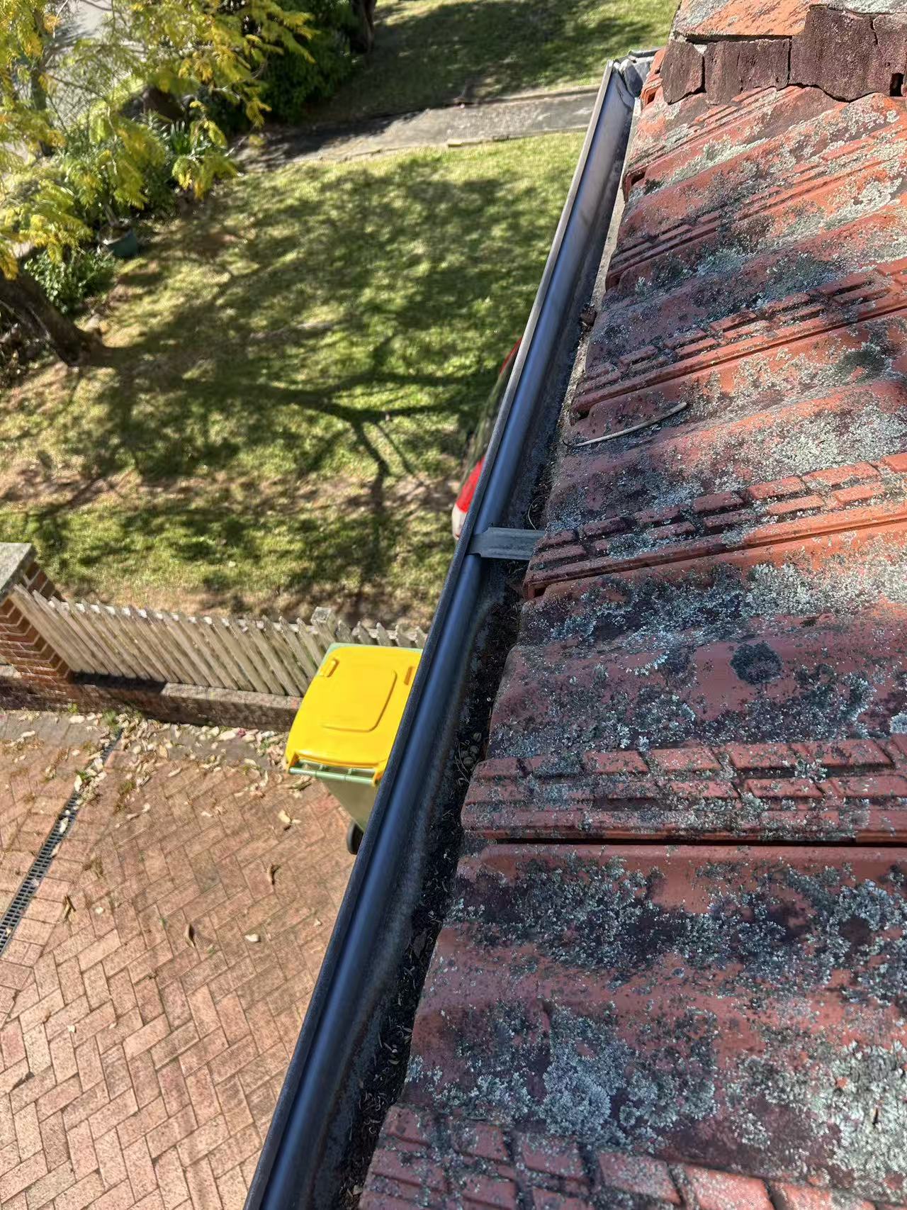 Roof-edge gutter beside weathered tiles