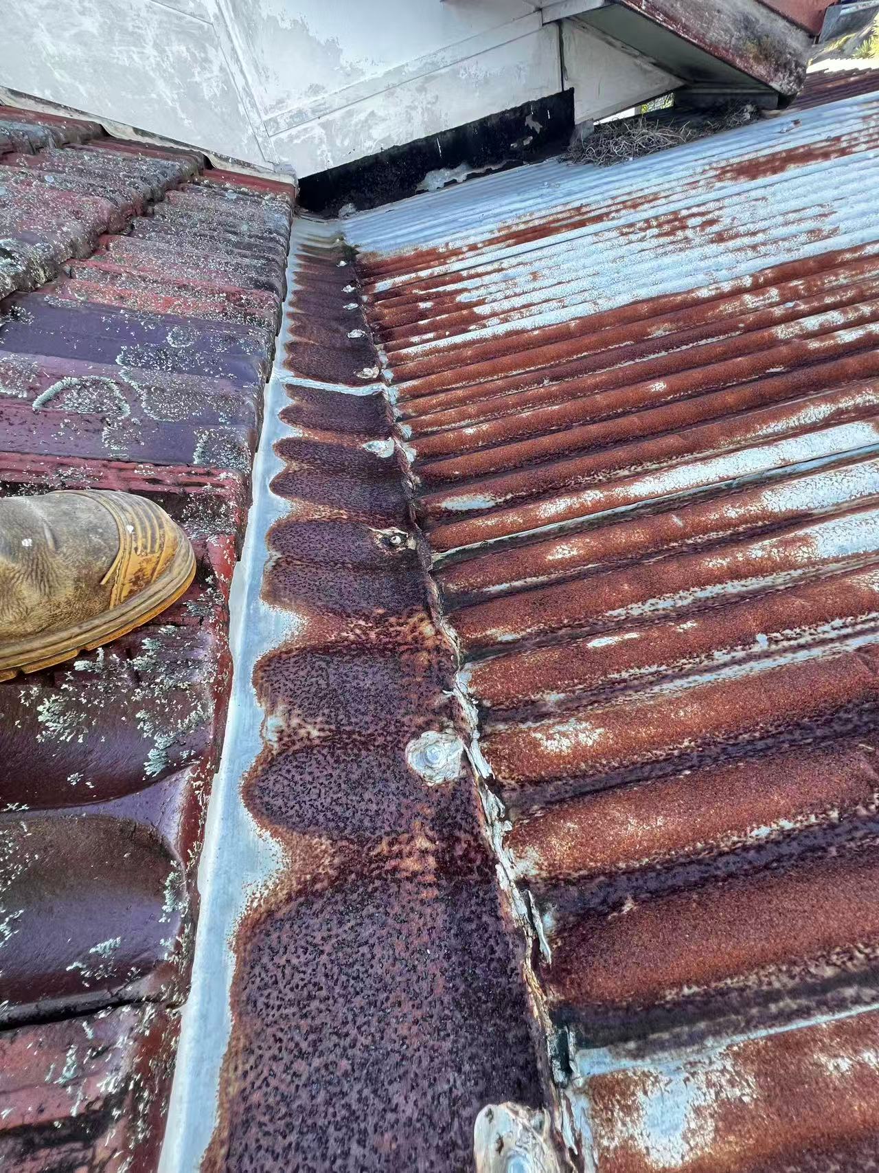Corroded metal sheets and junction flashing below the wall edge